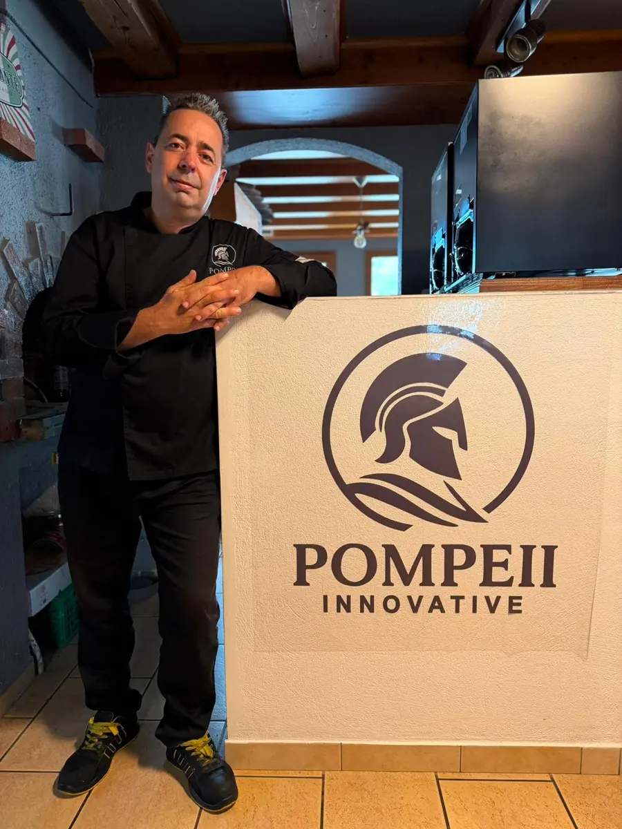 Armando, chef del ristorante Pompeii, davanti al logo Pompeii Innovative nella sala del ristorante